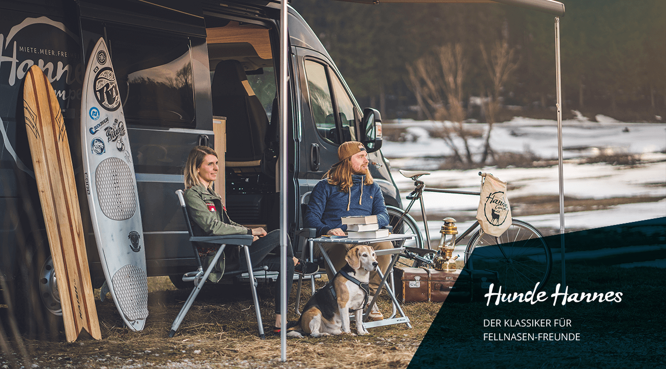 Wohnmobil mieten: Pärchen mit Hund sitzt vor dem Camper