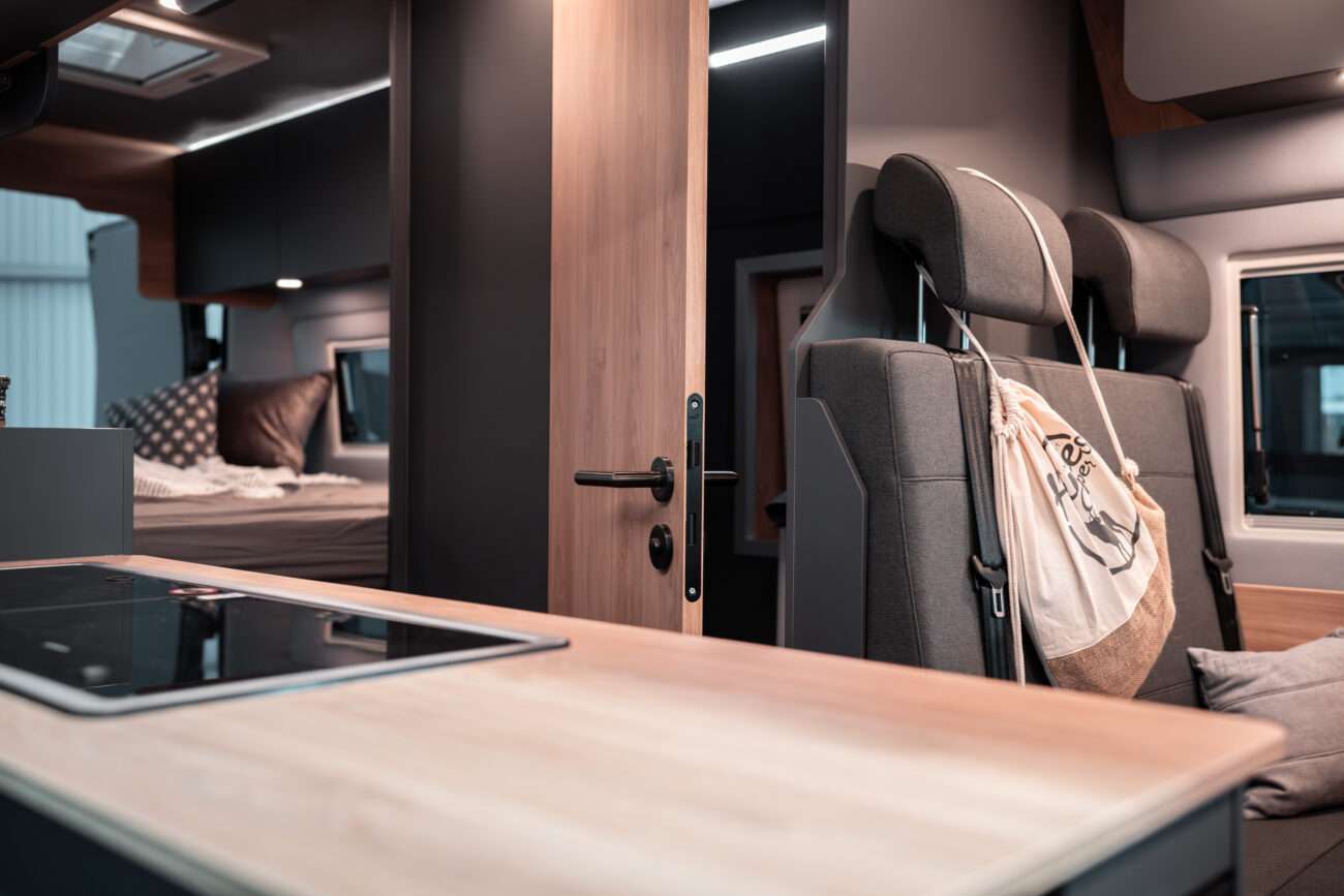 Wohnmobil mieten: Blick durch den Camper über Herd, Sitze und Bett