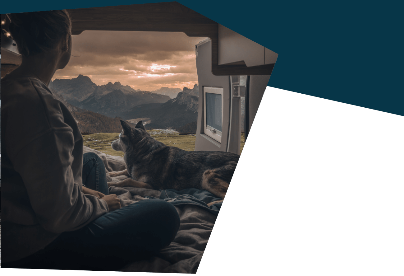 Wohnmobil mieten: Frau blick mit Hund aus dem Camper auf die Berge